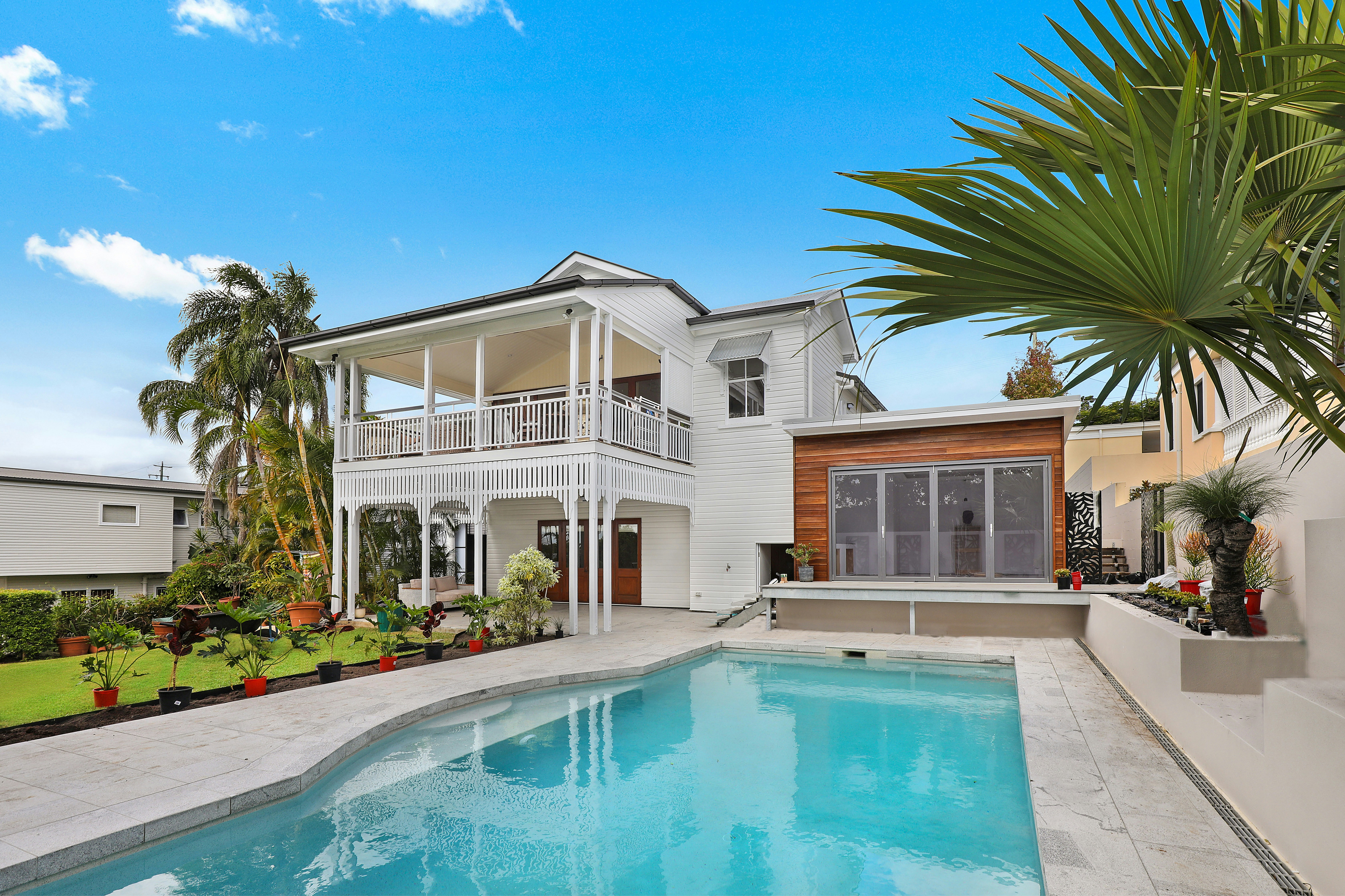 A beautiful white and red beach house with palm trees and a swimming pool